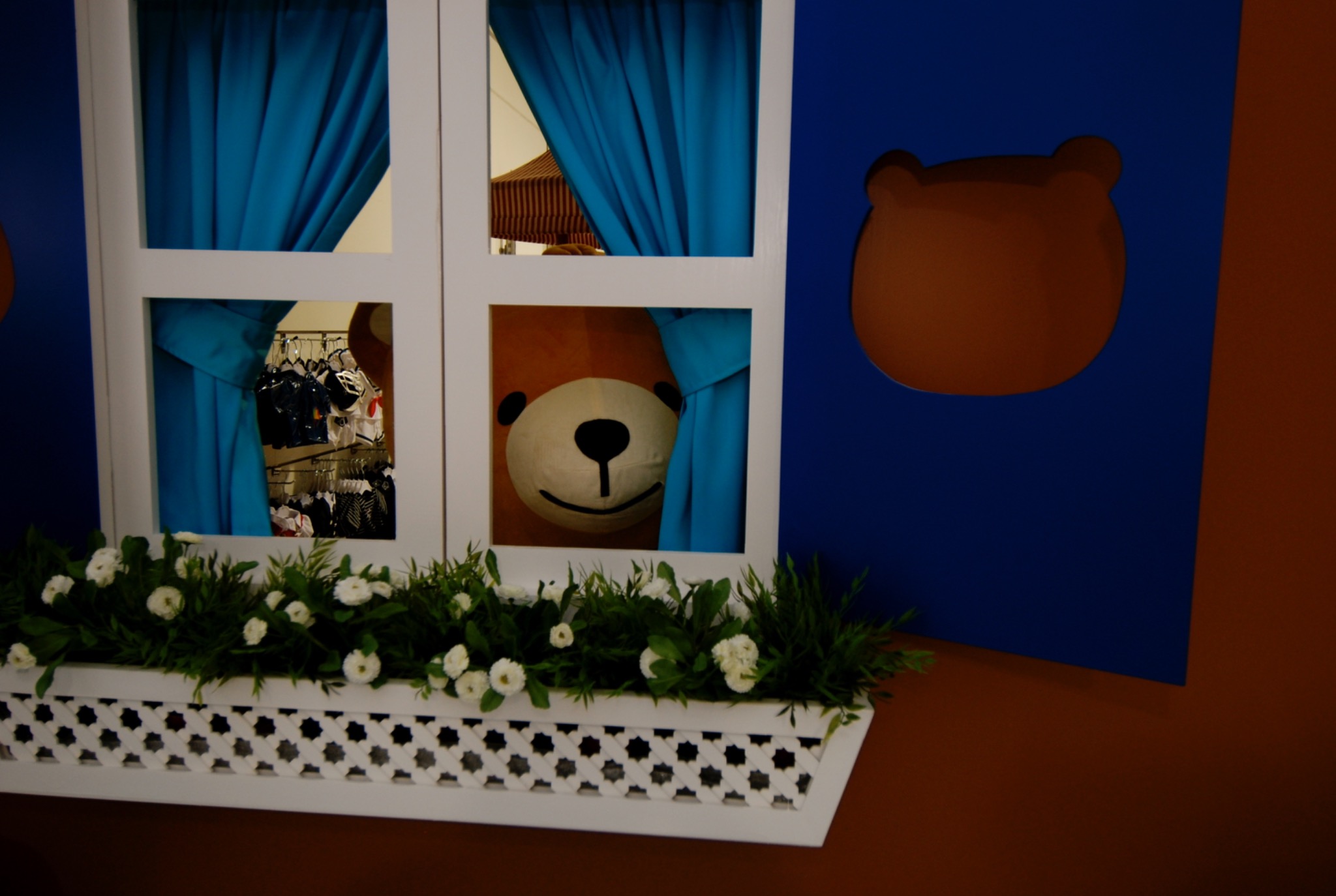 Window detail with bear, blue curtains and flowers