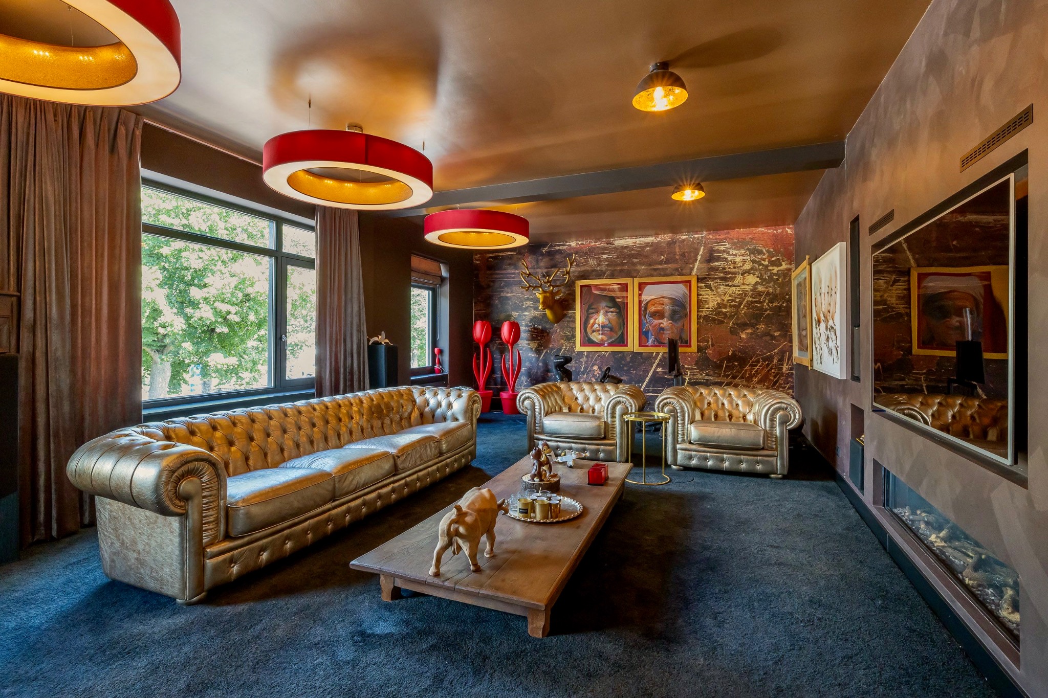 Gold Chesterfield seating, red pendant lighting and artwork in a complete living space